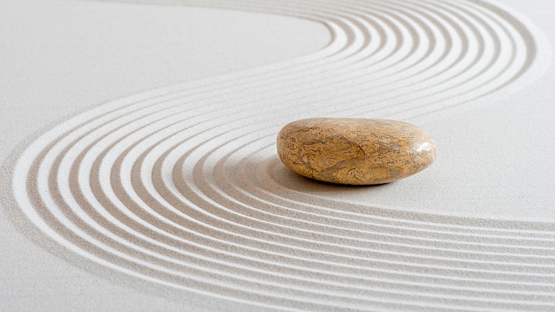 Ein Stein, welcher ruhig auf feinem Sand liegt