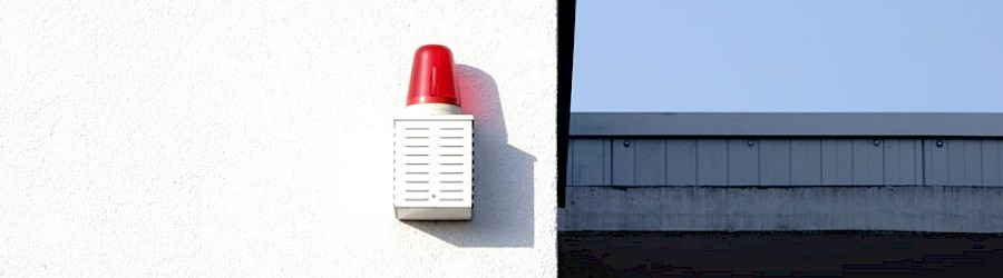 Signallampe hängend an einer weißen Wand und wirft einen Schatten