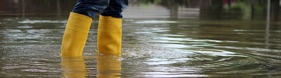 Person mit gelben Gummistiefeln im Wasser